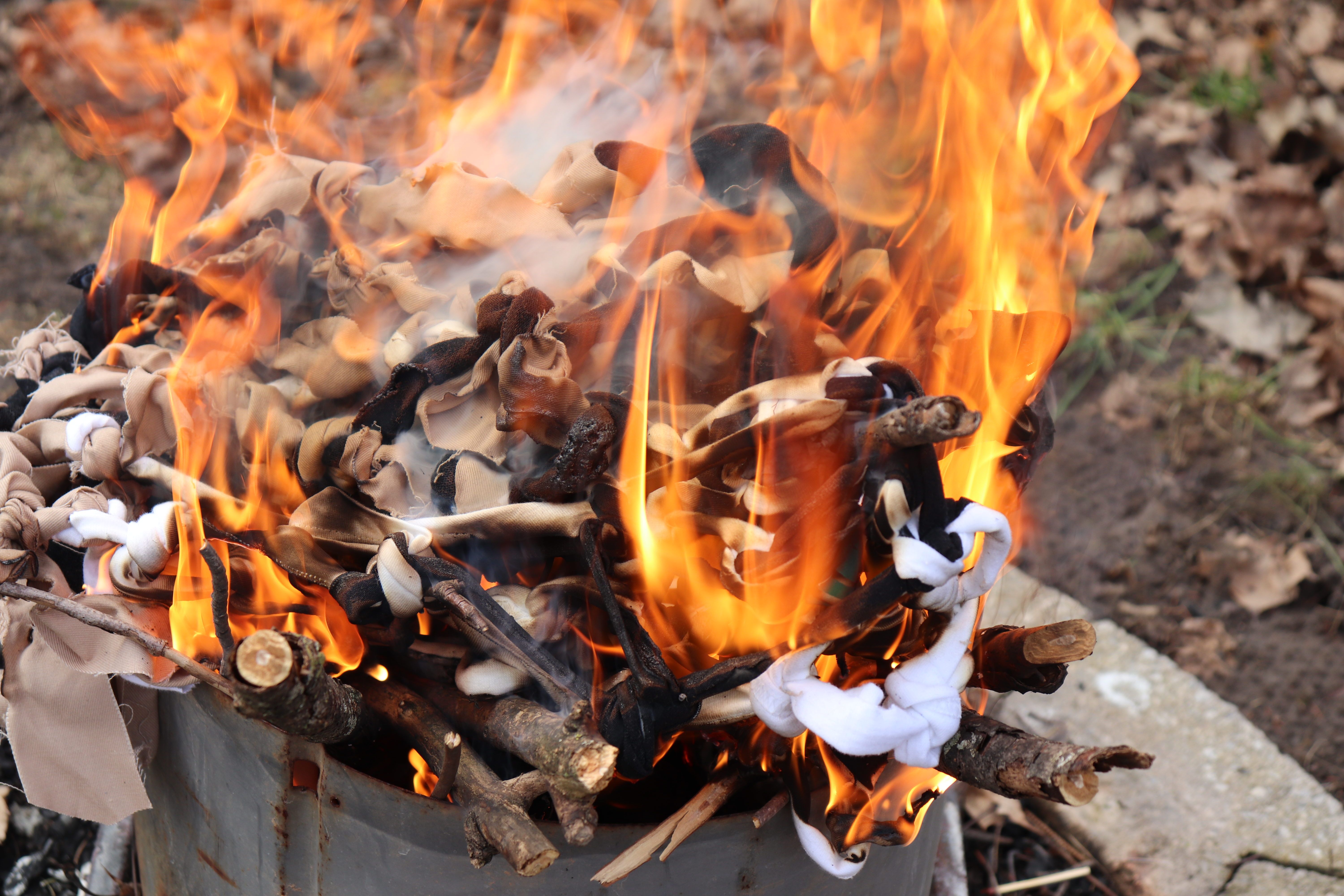 Photo of a net made of tied-together fabric being burned in a fire.